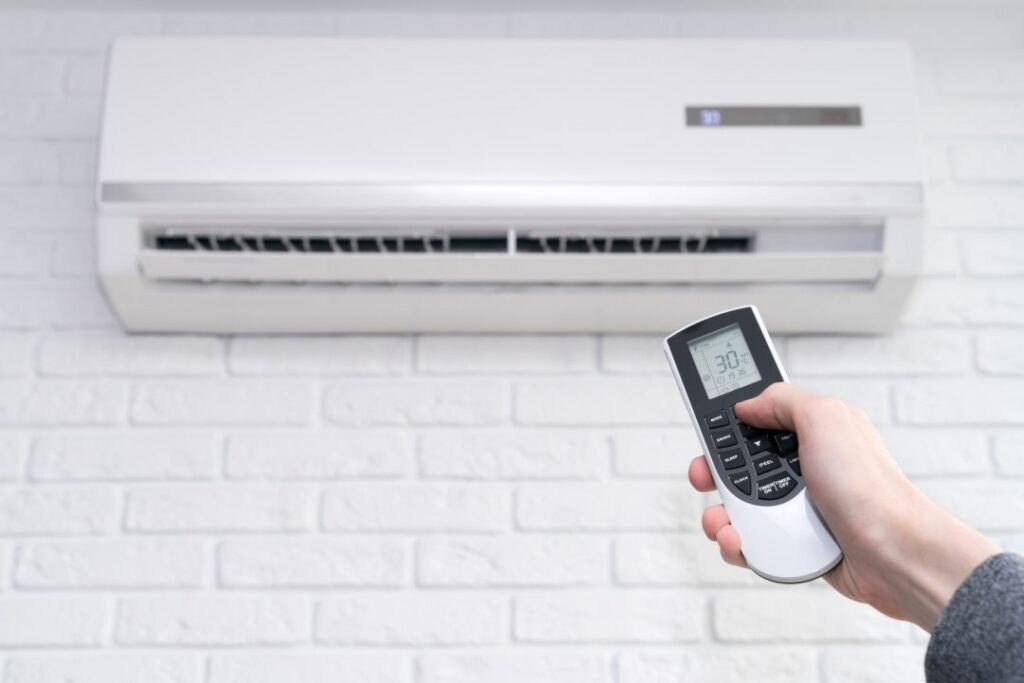 Hand and remote pointing at a ductless wall head HVAC unit